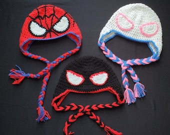 May include: Three crocheted hats with eye designs. The hats are red, white, and black with matching braided ties.