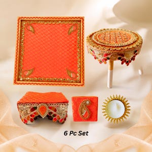 May include: A 6-piece set featuring a square orange tray, a raised circular platform, a rectangular box, a small square box with a paisley motif, and a circular candle holder, all decorated with gold trim, sequins, and the text 6 Pc Set.