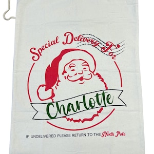 May include: A white canvas Santa sack with a red circle and a cartoon image of Santa Claus. The text "Special Delivery For Charlotte" is printed in red and green on the sack. The text "If undelivered please return to the North Pole" is printed in black at the bottom of the sack.