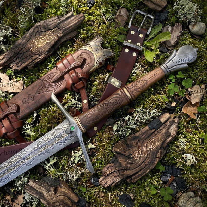 May include: A detailed image of a Viking sword with a brown leather sheath and belt. The sword features an ornate handle and blade with a green gem. The sheath and handle are intricately carved with patterns. The background is moss and wood.
