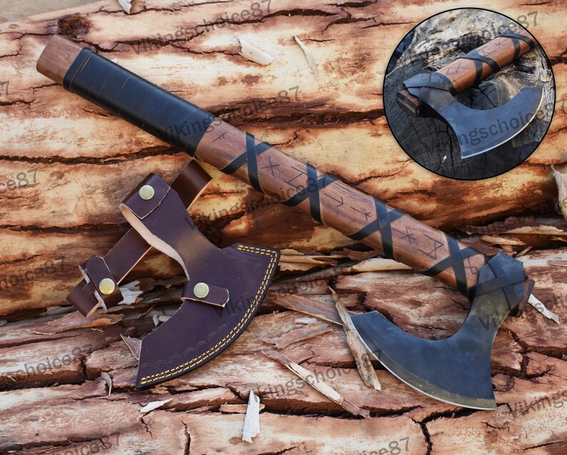 May include: A black and brown Viking axe with a leather handle and a leather sheath. The axe has a curved blade and is decorated with runes.