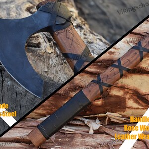 May include: A black axe with a wooden handle wrapped in leather. The blade is made of carbon steel and the handle is made of rose wood. The handle is decorated with runes.