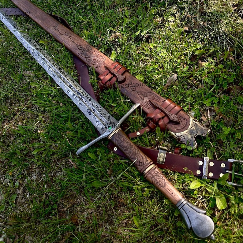 May include: A detailed image of a longsword with a patterned blade and wooden handle, resting on grass. The sword is accompanied by a brown leather sheath and belt, featuring intricate carvings and metal accents. The overall aesthetic is reminiscent of historical weaponry.