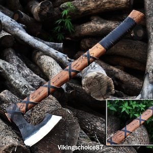 May include: A black-handled axe with a wooden shaft and a black leather wrap. The axe head is made of steel and has a sharp edge. The shaft is decorated with runes and the number "87".