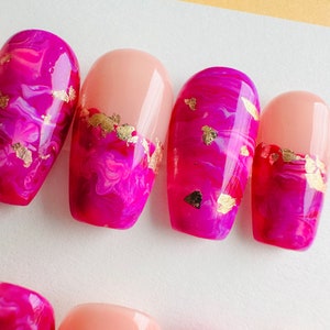 May include: Pink and gold swirl nail polish design with a pink and gold accent nail.