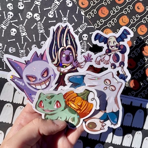 Op de afbeelding: Een verzameling kleurrijke, holografische stickers met verschillende stripfiguren. De stickers bevatten een paarse Gengar met een brede grijns, een groene Bulbasaur en andere personages met Halloween- en spookachtige thema's. De achtergrond heeft een Halloween-thema.