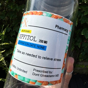 May include: A clear glass jar with a silver lid and a label that reads "Pharmacy", "Rx #123456", "EFFITOL 200 MG", "EXPIRATION DATE: NONE", "Take as needed to relieve stress", "Refills: Unlimited", "Prescribed by: Dont Giveadamn MD."