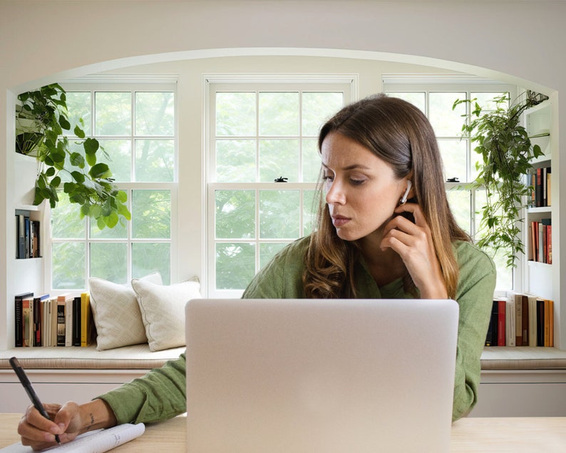 Virtual background of woman sitting at desk containing laptop and in front of window seat with bookshelf for zoom and virtual meeting streaming backdrop.
