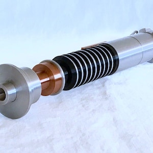 May include: A disassembled lightsaber with a silver and black handle, a copper coloured emitter, and a silver and black blade.