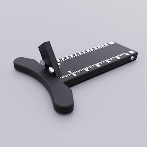 May include: A black tool with a ruler and a curved handle. The ruler has white markings and numbers. The tool has a vertical piece attached to the ruler with two silver rivets. The text "PDF" is visible on the handle.