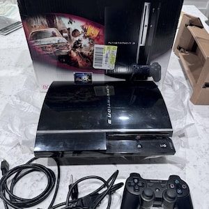 May include: A black PlayStation 3 console with a matching controller, power cord, and HDMI cable. The console is displayed with its original box, which features game graphics and the PlayStation 3 logo.