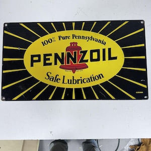 May include: Vintage Pennzoil metal sign with a black and yellow design. The sign features the text "100% Pure Pennsylvania PENNZOIL Safe Lubrication" in bold letters. The sign has a red bell logo and is rectangular.