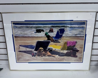May include: Framed print of a beach scene with four dogs relaxing on beach chairs. The dogs are a black Labrador, a brown Labrador, a black and white dog, and a brown and white dog. The beach chairs are blue, yellow, and green. The beach is sandy and the ocean is blue.