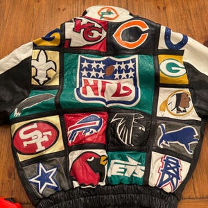 May include: A multi-colored leather jacket featuring a patchwork design of various NFL team logos and a large central NFL shield emblem. The jacket includes black, white, red, green, and yellow panels with embroidered team insignias throughout.