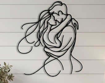Puede incluir: Una obra de arte mural de metal negro que representa a dos figuras abrazándose. La obra está montada en una pared blanca de tablones sobre una consola de madera. La mesa está decorada con un jarrón, velas y cestas tejidas.