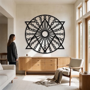 May include: A large black circular wall art piece featuring a geometric design with a central circle, radiating lines, and interconnected rings forming a star shape. The intricate pattern is symmetrical and composed of thin, dark metal-like lines.