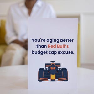 May include: A white card with a funny message about aging better than Red Bull's budget cap excuse. The card features a cartoon image of a Formula One race car.
