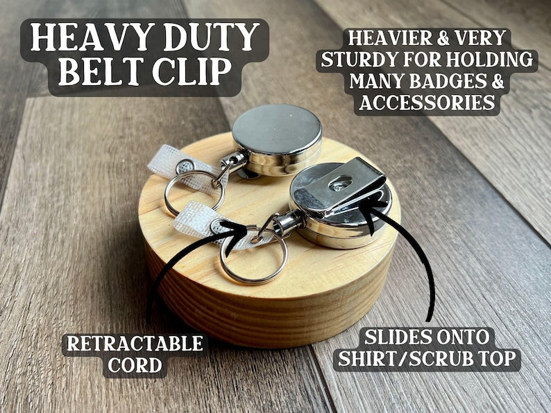 May include: A heavy-duty belt clip with a retractable cord. The clip is made of silver metal and has a sturdy design for holding badges and accessories. It slides onto a shirt or scrub top. The text on the image says "Heavy Duty Belt Clip".