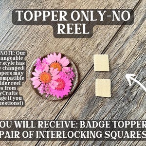 May include: A badge topper with pink and orange flowers encased in clear resin, accompanied by two small beige interlocking squares. The text reads "TOPPER ONLY-NO REEL" and "YOU WILL RECEIVE: BADGE TOPPER + PAIR OF INTERLOCKING SQUARES."