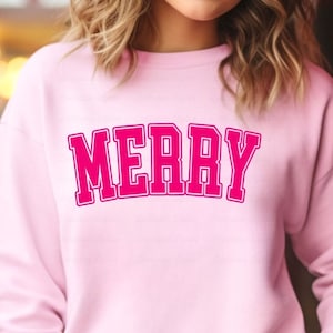 May include: Pink sweatshirt with the word "MERRY" in large, pink, outlined letters.