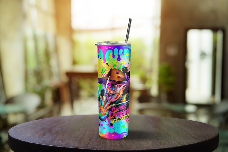 May include: A colorful stainless steel tumbler with a graphic of Freddy Krueger from the movie "A Nightmare on Elm Street". The tumbler has a black lid and a black straw. The graphic is surrounded by colorful paint splatters and the text "Sweet Dreams Are Made Of This".