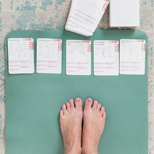 A green yoga mat with five cards laid out on top. The cards are labelled with different yoga poses: Mountain pose, Raised arms pose, Downward-facing dog, Half standing forward fold, and Standing forward fold.