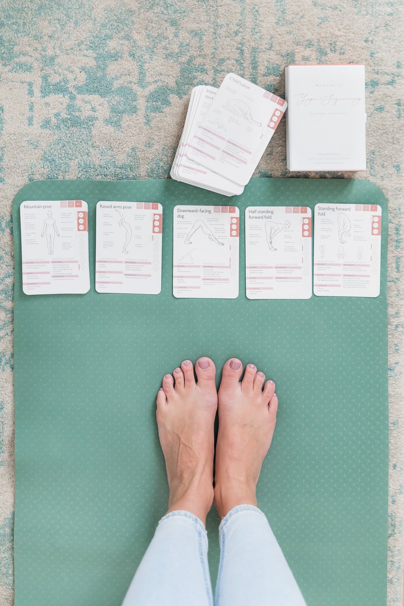 A green yoga mat with five cards laid out on top. The cards are labelled with different yoga poses: Mountain pose, Raised arms pose, Downward-facing dog, Half standing forward fold, and Standing forward fold.