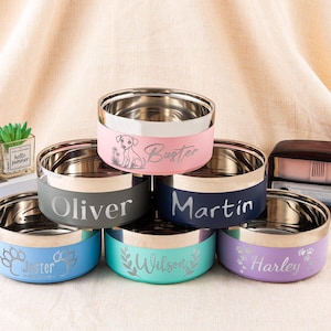 Może przedstawiać: Sześć misek dla zwierząt ze stali nierdzewnej z kolorowymi paskami. Każda miska ma inną nazwę lub wzór: "Buster" z ilustracją psa, "Oliver", "Martin", "Jester" z odciskami łap, "Wilson" i "Harley".