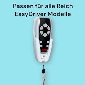 Könnte beinhalten: Weiße Wandhalterung für eine Fernbedienung mit einer schwarzen und roten Fernbedienung im Inneren. Die Fernbedienung hat eine schwarz-weiße Tastenanordnung mit einem runden Knopf in der Mitte. Die Wandhalterung hat eine kleine weiße Schlaufe unten mit einem schwarzen Band.
