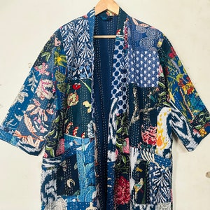 Può includere: Un kimono patchwork blu e bianco con motivi floreali e geometrici. Il kimono ha una silhouette lunga e fluida ed è perfetto per essere sovrapposto a un vestito o pantaloni.