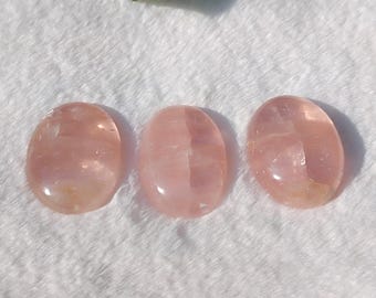 Puede incluir: Tres piedras ovaladas pulidas de color rosa y blanco. Las piedras son lisas y pulidas.