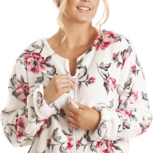 Puede incluir: Batista blanca de felpa con estampado floral en tonos rosa y gris. La bata tiene cierre de cremallera y mangas largas.
