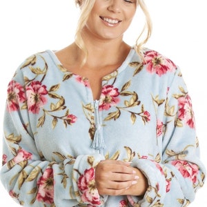 Puede incluir: Una bata de felpa azul claro con estampado floral. La bata tiene una cremallera y un borla en el tirador de la cremallera.