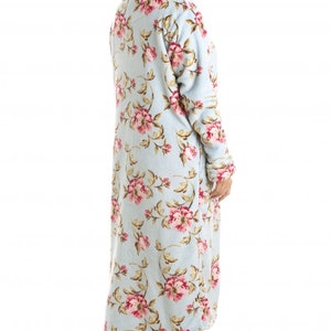 Puede incluir: Una bata larga de color azul claro con estampado floral. La bata tiene mangas largas y cuello en V.