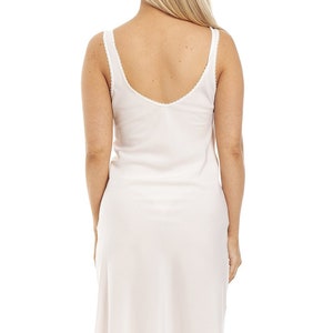 May include: A white slip dress with a scoop neck and thin straps. The dress has a lace trim around the neckline.