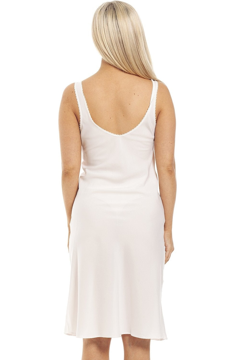 May include: A white slip dress with a scoop neck and thin straps. The dress has a lace trim around the neckline.