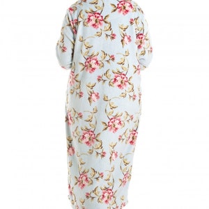 Puede incluir: Una bata larga de color azul claro con estampado floral con flores rosas y marrones. La bata tiene mangas largas y cuello en V.