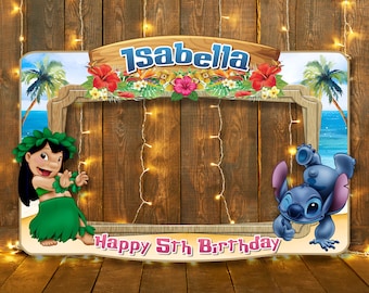 May include: A photo booth prop featuring a tropical luau theme with a blue sky, palm trees, and flowers. The prop has a cutout in the middle for a person's face. The text "Isabella Happy 5th Birthday" is on the bottom of the prop. The characters Lilo and Stitch are on either side of the cutout.