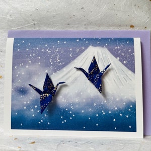 Carte de Noël faite main avec deux grues en origami violettes et le mont Fuji dans la neige