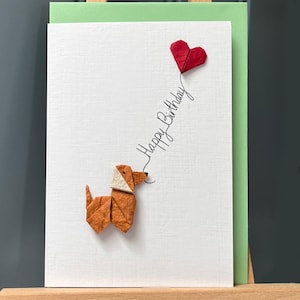 Carte de joyeux anniversaire faite main en origami chien marron debout et ballon coeur rouge, papier mûrier texturé pour les amoureux des chiens