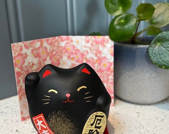 Japanische Maneki Neko schwarze Glückskatze zum Schutz mit Matte und Grafikkarte. Feng Shui.