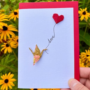 Handgefertigte Grußkarte Origami Kranich goldfarbe japanisches Chiyogami Papier mit rotem Herzballon 'Love'