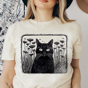 ヴィンテージフローラルフォークロア黒猫Tシャツ、コテージコア美的シャツ、リノプリントTシャツ、猫好きTシャツ、フォークアート動物シャツ彼女へのギフト