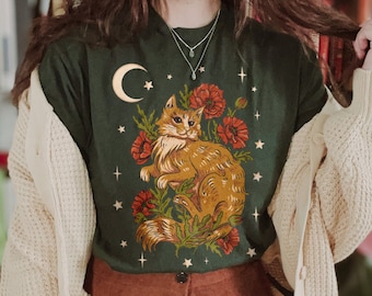 May include: A green t-shirt with a graphic of a cat sitting in a field of flowers under a crescent moon. The cat is orange and white with green eyes. The flowers are red and the background is dark green.