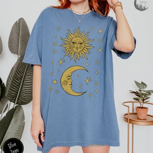 Puede incluir: Una camiseta azul de gran tama&ntilde;o con un gr&aacute;fico amarillo de sol y luna. El sol y la luna tienen caras y est&aacute;n rodeados de estrellas. La camiseta tiene un corte holgado y es perfecta para el uso diario.