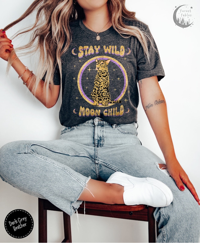 May include: Dark grey heather t-shirt with a graphic of a leopard sitting in a circle with the text "Stay Wild Moon Child".