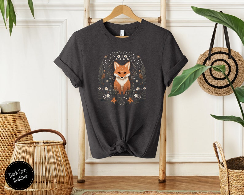 May include: Dark grey heather t-shirt with a graphic of a fox surrounded by flowers. The fox is orange and white with a black nose and eyes.