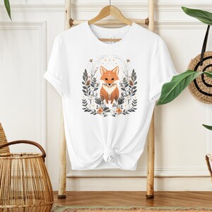 May include: White t-shirt with a graphic of a fox surrounded by flowers and leaves. The fox is orange and white with a black nose and eyes.