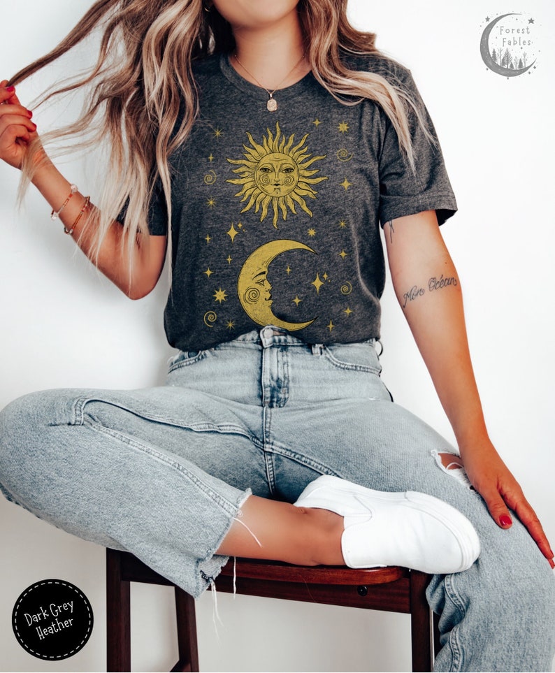 May include: A dark grey heather t-shirt with a graphic of a sun and moon with stars. The sun and moon are yellow and the stars are white.