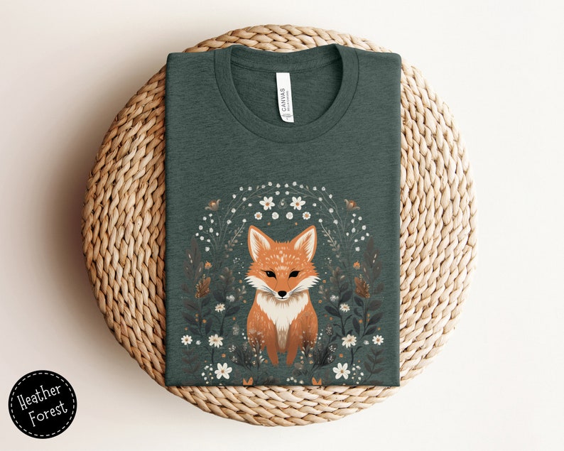 May include: A dark green t-shirt with a graphic of a fox surrounded by white flowers. The fox is orange and white with a black nose and eyes.